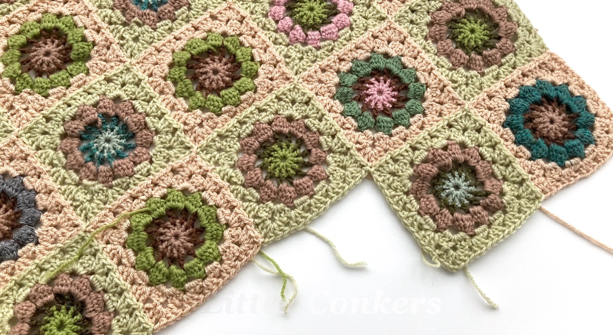 A series of square crocheted blocks being joined together into a blanket panel